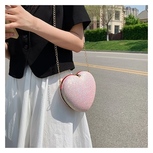 Detailed view of heart-shaped crossbody bag featuring pink glitter material and gold chain
