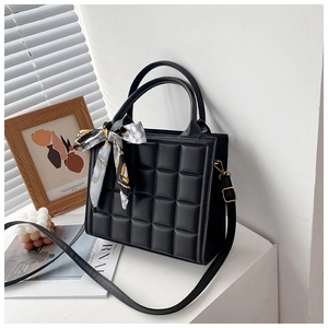Détail d'un sac à main matelassé noir avec foulard en soie et texture cuir élégante