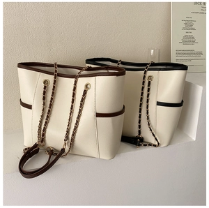 Close-up of stylish chain tote bag with contrasting trim and golden metal rings