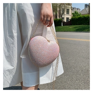 Close-up of pink glitter heart-shaped evening bag with gold metal chain strap