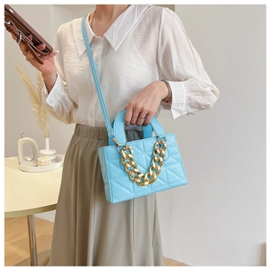 Close-up of light blue quilted crossbody bag featuring a thick gold chain decoration