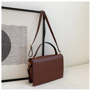 Detail of dark brown leather handbag featuring golden hardware and elegant handle