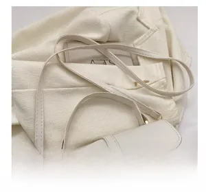 Close-up of cream crocodile pattern leather bag with fine shoulder strap and gold buckle