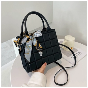 Détail d'un sac à main matelassé avec un foulard en soie élégant noué sur la poignée