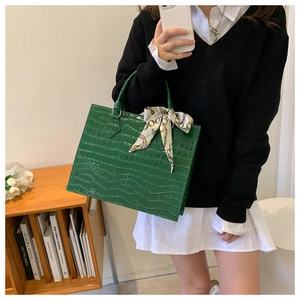 Green croc-effect tote bag with chain pattern silk scarf detail in a lifestyle setting