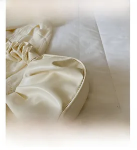 Detailed view of cream-colored pleated faux leather on a stylish croissant shoulder bag