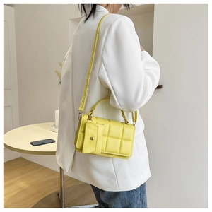 Detail shot of bright yellow quilted square shoulder bag with small coin purse charm