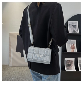 Detail of silver glitter quilted crossbody bag with stylish clear acrylic chain strap
