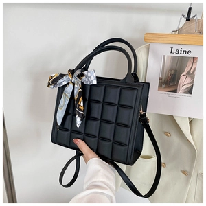 Détail d'un sac à main matelassé noir avec foulard en soie imprimé sur la poignée et bandoulière