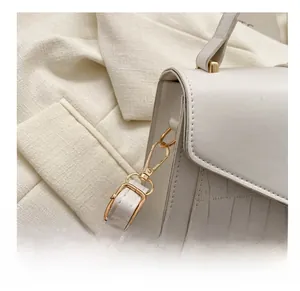 Close-up of white crocodile pattern bag with golden swivel hook and leather strap