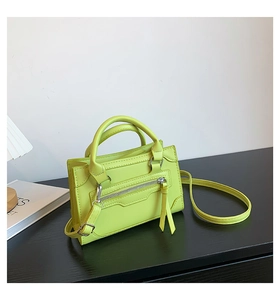 Detail of neon green leather crossbody bag with front zipper and dual handles