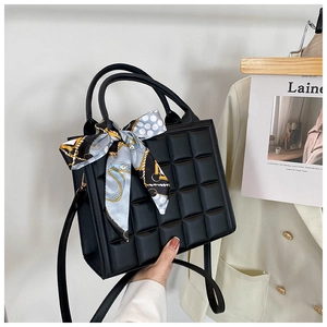 Gros plan du sac à bandoulière noir matelassé avec foulard en soie imprimé sur la poignée