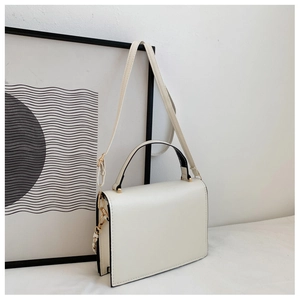 Macro shot of minimalist cream leather crossbody bag with elegant gold hardware