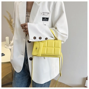 Detail of a bright yellow quilted square crossbody bag with matching mini pouch and strap