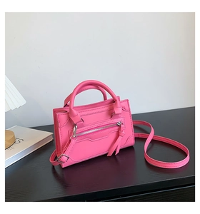 Detailed view of pink leather handbag featuring decorative zippers and long tassels
