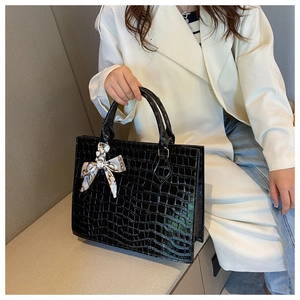 Detail of black faux crocodile skin texture and printed silk scarf on handbag