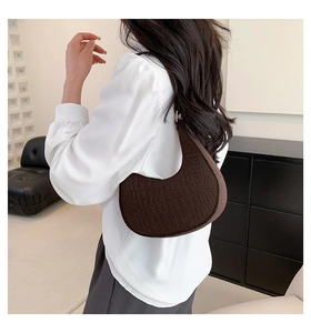 Close-up of dark brown crocodile pattern half-moon shoulder bag with retro texture