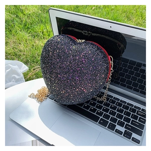 Detail of a heart-shaped evening bag with black sequins and a golden chain strap