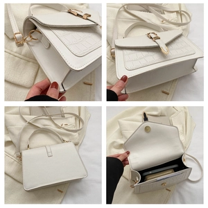 Detail view of white croc-embossed small square bag with gold hardware and interior space