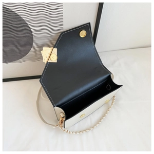 Detail of crossbody bag with dual straps, contrast flap, and golden magnetic closures