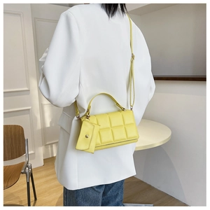 Detail of yellow quilted crossbody bag with matching coin purse on a white blazer