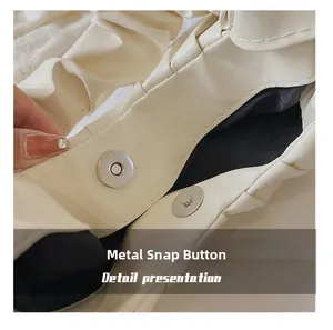 Detailed close-up of the magnetic metal clasp on this stylish beige pleated cloud bag