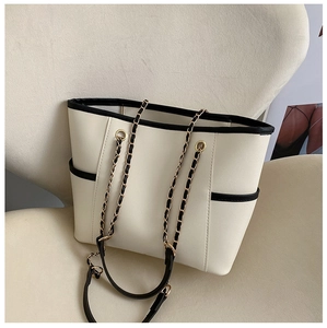 Detail of cream white tote bag featuring black contrast piping and woven chain strap