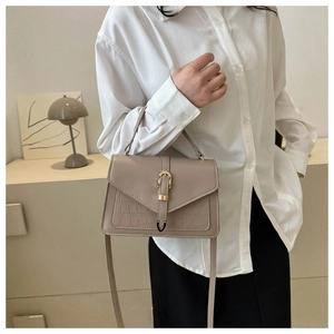 Detail of khaki crossbody bag featuring crocodile texture flap and gold metal buckle