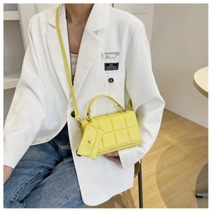 Close-up of bright yellow quilted square handbag with matching mini pouch and crossbody strap