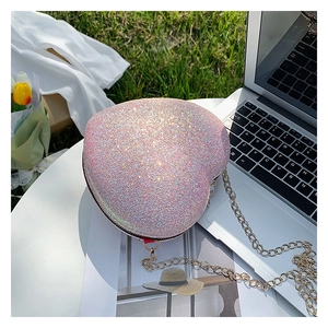 Macro view of pink heart-shaped glitter chain bag with golden strap on a table