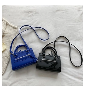 Overhead view of royal blue and black mini handbags on white fabric with a tweed jacket