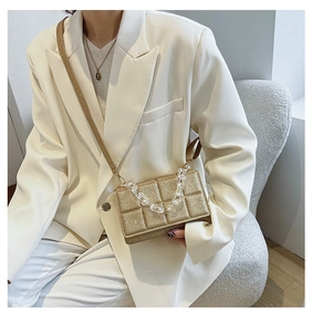 Detail of gold sequin quilted crossbody bag with stylish acrylic chain and strap