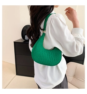 Detail of green crocodile texture on a retro crescent bag worn with a white shirt