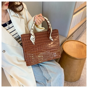 Brown crocodile pattern square handbag with decorative silk scarf on handle and metal buckle