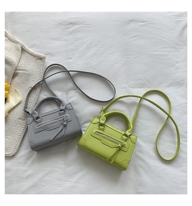 Detail of gray and lime green mini crossbody bags with decorative tassels and matte texture