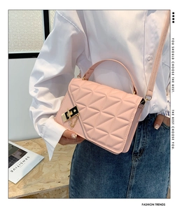 Pink quilted crossbody bag with gold lock and chain detail worn by a model