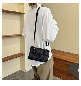 Detail of black quilted leather shoulder bag with chunky acrylic chain and gold hooks