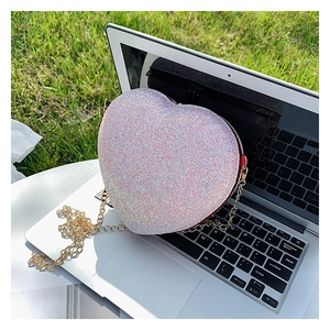 Detail of pink heart-shaped sequin bag with gold chain strap on laptop keyboard