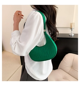 Close-up of emerald green crescent shoulder bag with crocodile pattern and gold hardware