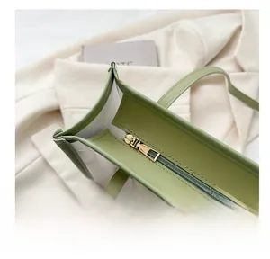 Close-up of smooth gold metal zipper on green leather and transparent PVC beach tote