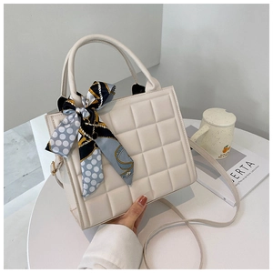 Détail du sac à main matelassé crème avec un élégant foulard en soie sur la poignée