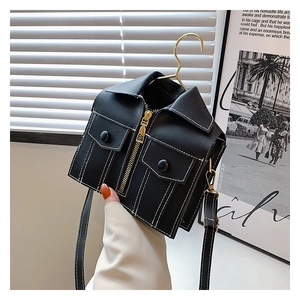 Close-up of black jacket-shaped crossbody bag with gold zippers and white stitching details