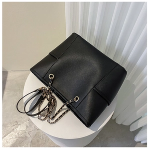 Close-up of black PU leather tote bag with gold chain strap and fine stitching detail