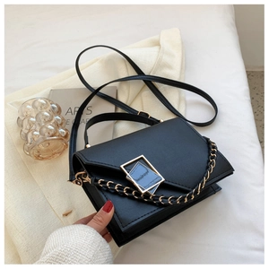 Top view of black crossbody bag with gold square buckle on beige knit fabric
