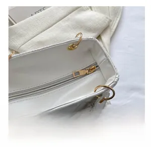Close-up of the smooth golden metal zipper detail and interior lining of the white handbag