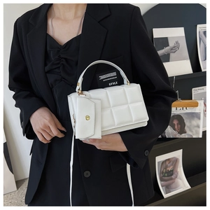 Close-up of white quilted leather handbag with matching mini coin purse and gold hardware