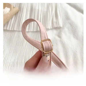 Detail view of adjustable pink leather shoulder strap with square golden metal buckle
