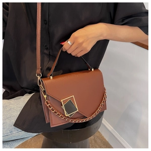 Detail view of dark brown leather crossbody bag with geometric buckle and chain