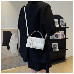 Detailed view of a white quilted crossbody bag with a small pouch on a black blazer