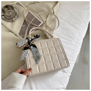 Détail d'un sac à main matelassé blanc crème orné d'un élégant foulard en soie imprimé